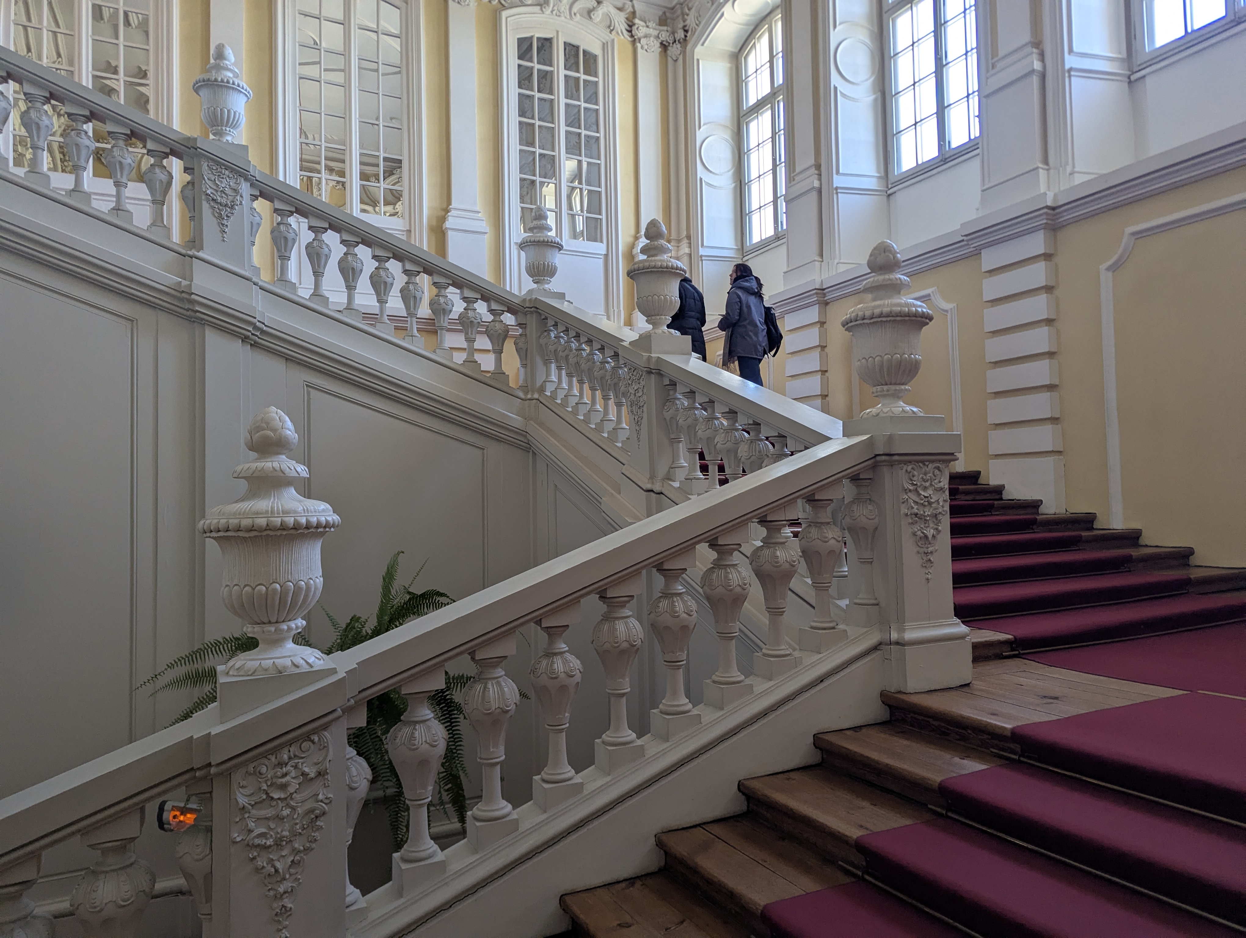 Rundalės rūmų iškilmingieji laiptai su baltomis stuko balustradėmis ir vyno spalvos kilimu