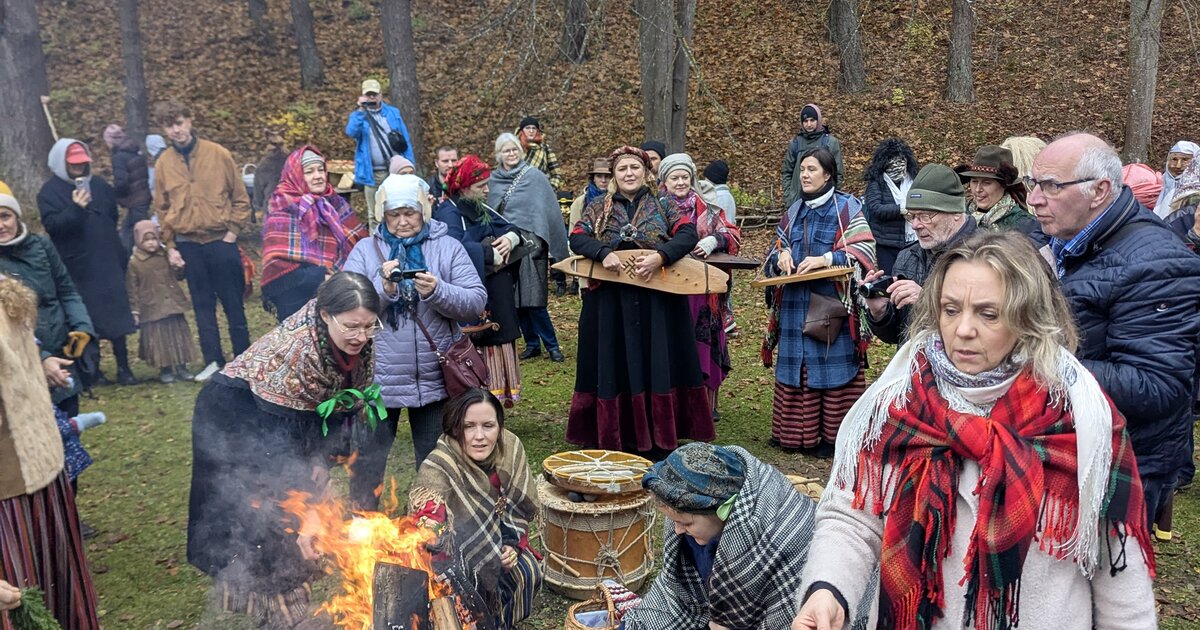 Lankytojai tautiniais drabužiais prie Mārtiņdienos laužo Latvijos etnografiniame lauko muziejuje, Rīgoje.